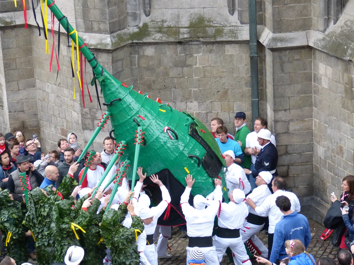 Le Dragon du Doudou de Mons avec sa longue queue rigide décorée de rubans, devant la Collégiale Sainte-Waudru.