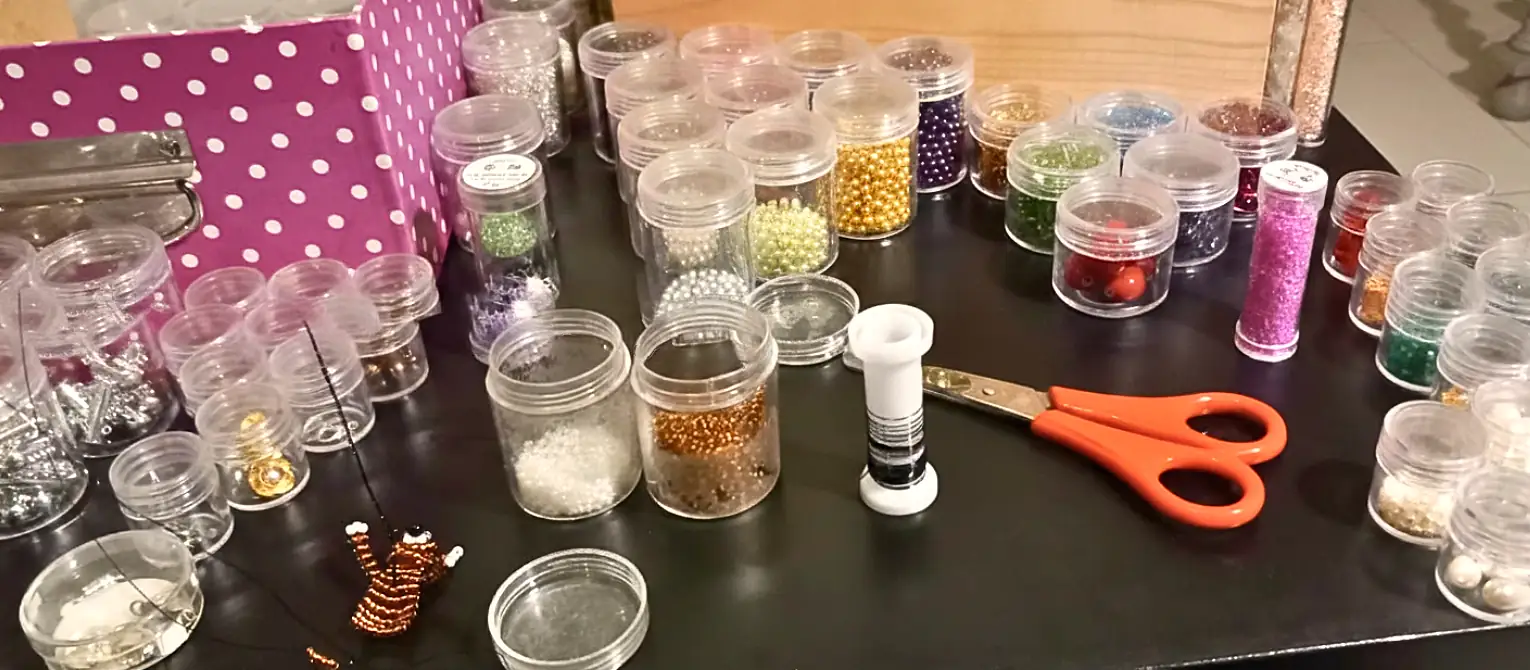 Vue d'ensemble d'un espace de travail créatif avec des perles de rocaille de diverses couleurs et des outils pour la fabrication de bijoux artisanaux