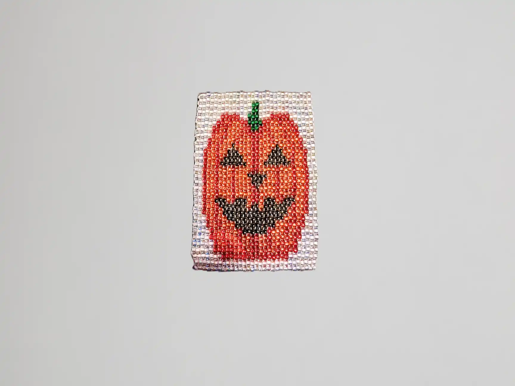 Image en perles faite main avec motif citrouille aux couleurs vives sur fond argenté