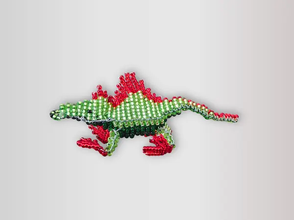 Figurine artisanale d'un petit dragon en perles de rocaille vertes et rouges, fait main en Belgique.