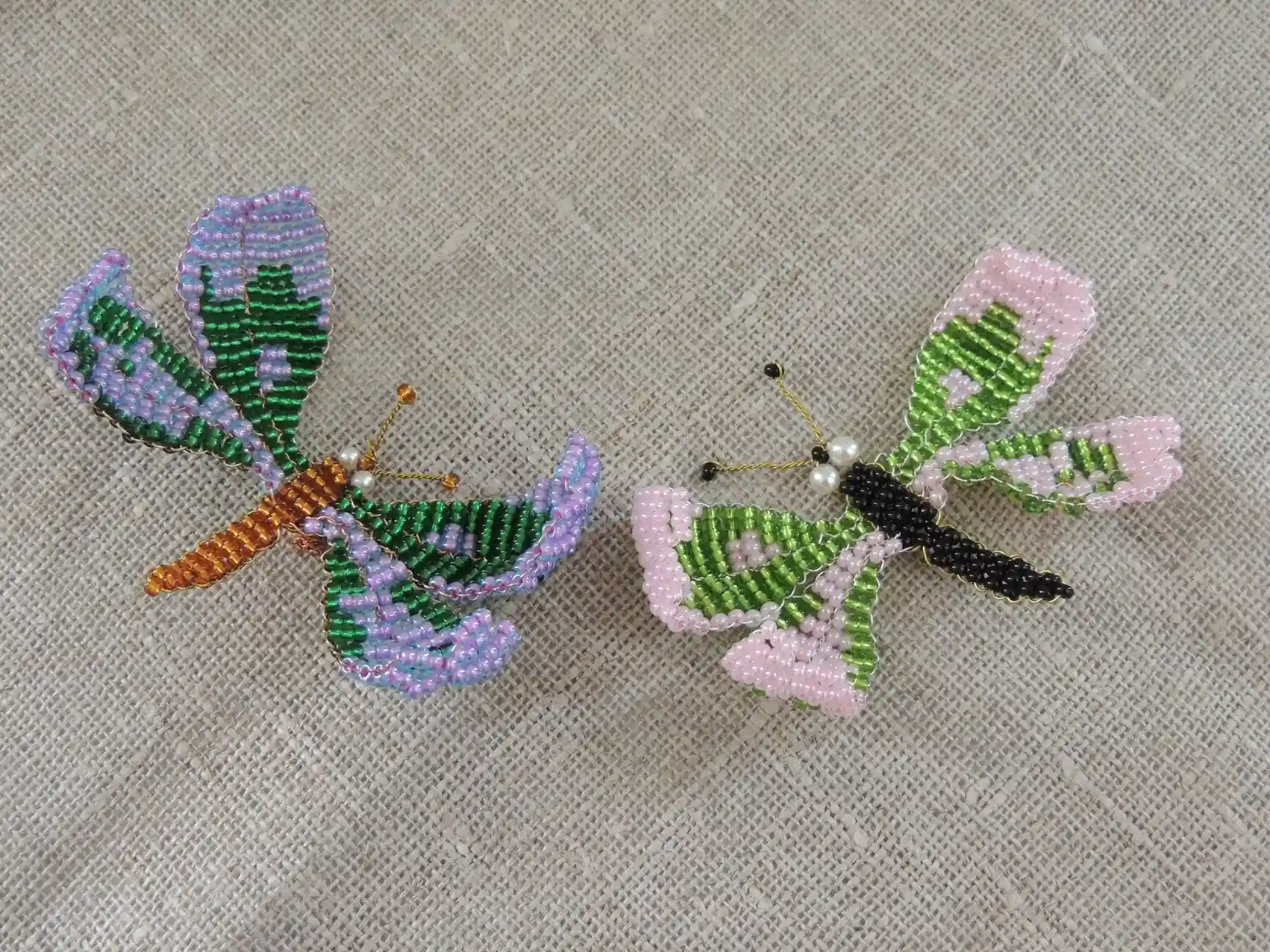 Deux papillons en perles aux tons violets, roses et verts.