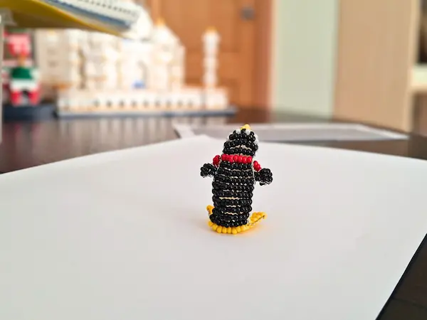 Vue de dos du pingouin artisanal en perles, mettant en valeur le tissage symétrique en perles noires et blanches. La structure en 3D permet à la figurine de tenir debout toute seule.