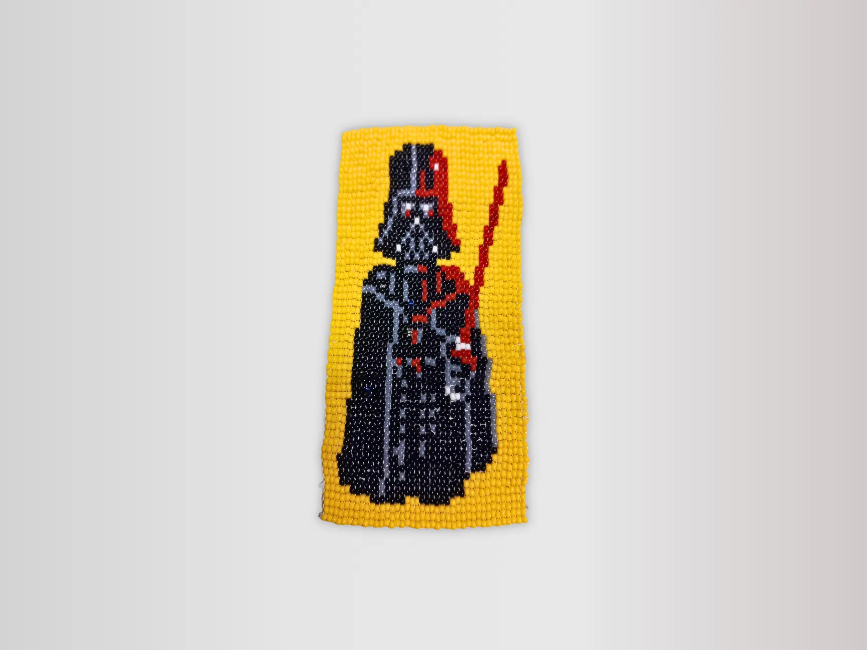 Tissage de perles Dark Vador avec sabre laser rouge sur fond jaune, fait main par A la petite perle.