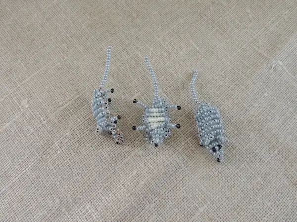 Trio de souris miniatures en perles gris perle, vue de face, de dos et de côté sur tissu de lin.